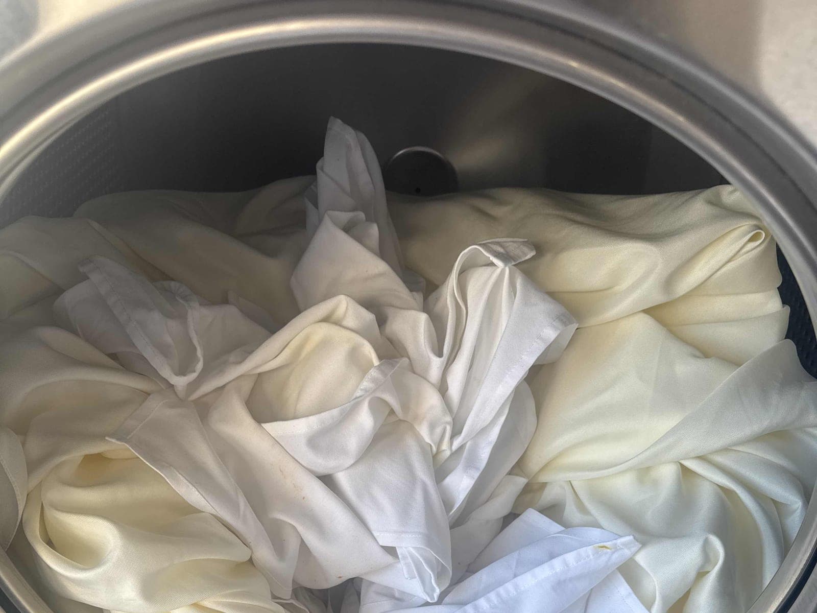 White linens loaded into a large-capacity commercial washer